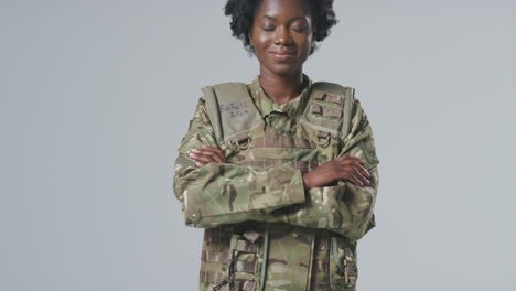retrato de estudio de larga duración de una joven soldado sonriente en uniforme militar en un fondo plano
