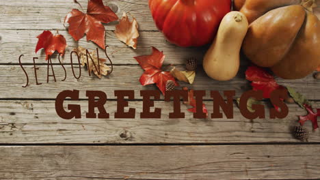 seasons greetings text animation over autumn leaves, pumpkins, and wooden background