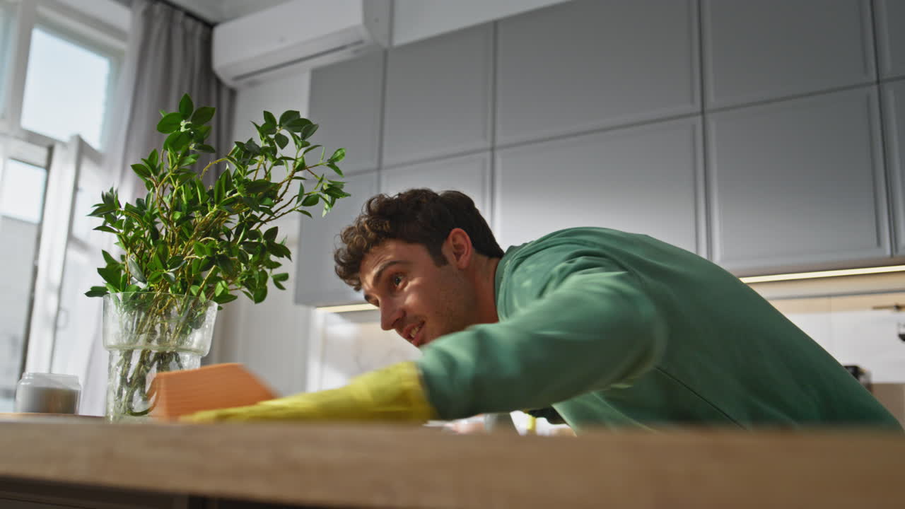 Careful man polishing table kitchen closeup. Guy wiping counter cleaning house