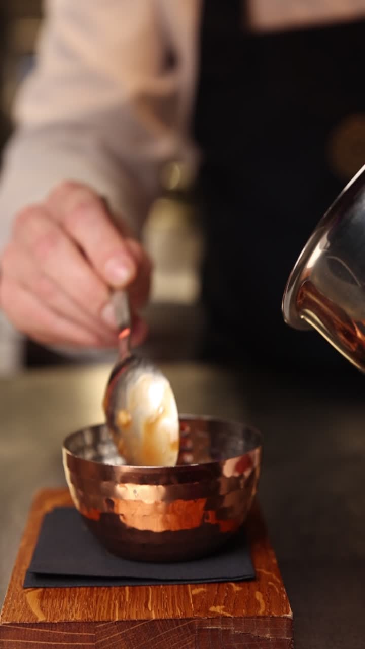Chef Pouring and Stirring Liquid in a Copper Bowl