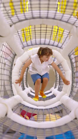 a little girl crawls through a soft and colorful tunnel at an indoor playground, enjoying her active and playful childhood
