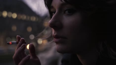 Young-woman-in-a-black-coat-standing-on-a-terrace-and-smoke-2