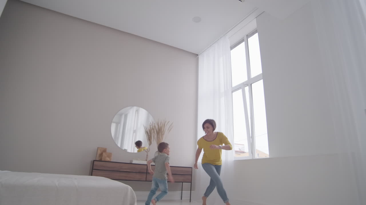 mamá feliz con un niño jugando a ponerse al día en la casa en un apartamento brillante. correr por la casa riendo y sonriendo. jugar a la etiqueta con mi hijo. jugar al escondite