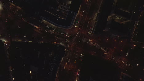 AERIAL:-Beautiful-Overhead-Shot-of-busy-intersection-at-night-with-Car-traffic-and-city-lights