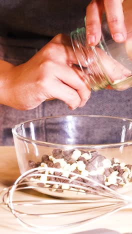 persona añade chispas de chocolate al cuenco de mezcla