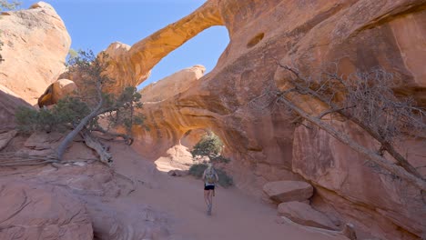 joven mujer rubia excursionista en los arcos dobles en el parque nacional arches, utah