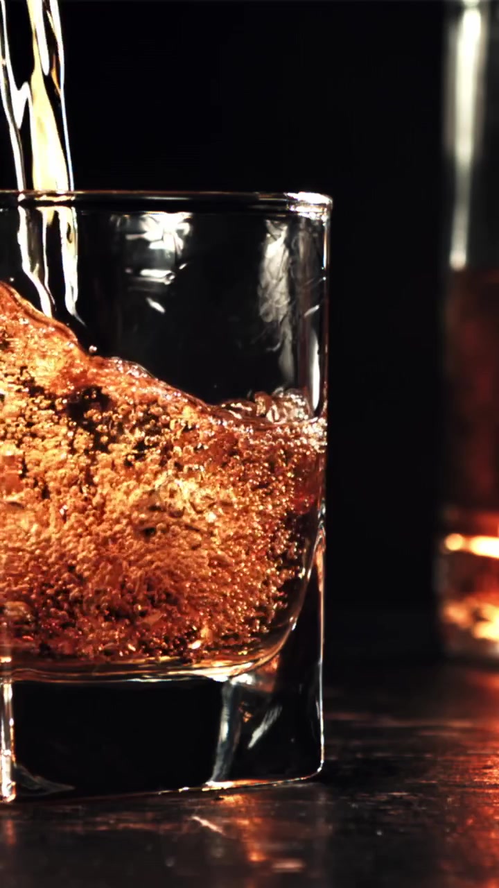 Whisky dorato che si versa in un bicchiere al rallentatore