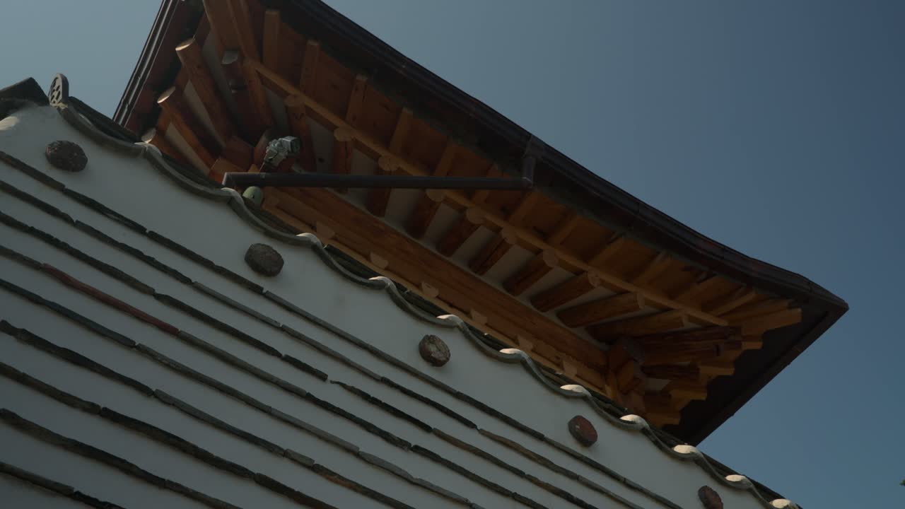 Intricate details of a traditional Korean Hanok house, highlighting its wooden beams, tiled eaves, textured walls in Bukchon Hanok Village, Seoul - Low angle dynamic parallax view