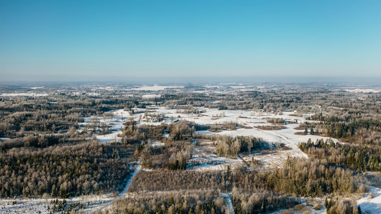 Aerial panoramic view of winter in countryside. Snow covered ground and forest in early morning sun. Frost over the trees in frozen forest landscape. Beautiful nature.