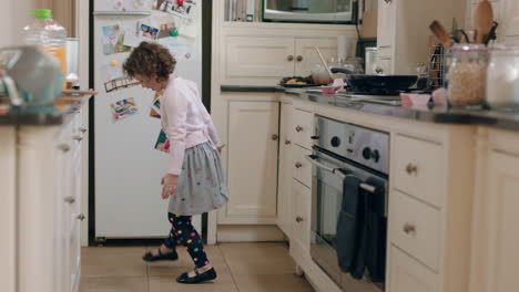 happy little girl dancing in kitchen having fun doing funny dance moves enjoying weekend at home