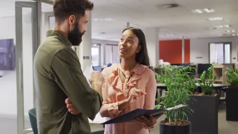 video of happy diverse businesswoman and businessman talking in office