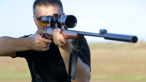 hunter in camouflage aims gun at object in forest man in comfortable camouflage clothes hunts outdoor in forest hunting alone hunter in camouflage aims gun at object in forest