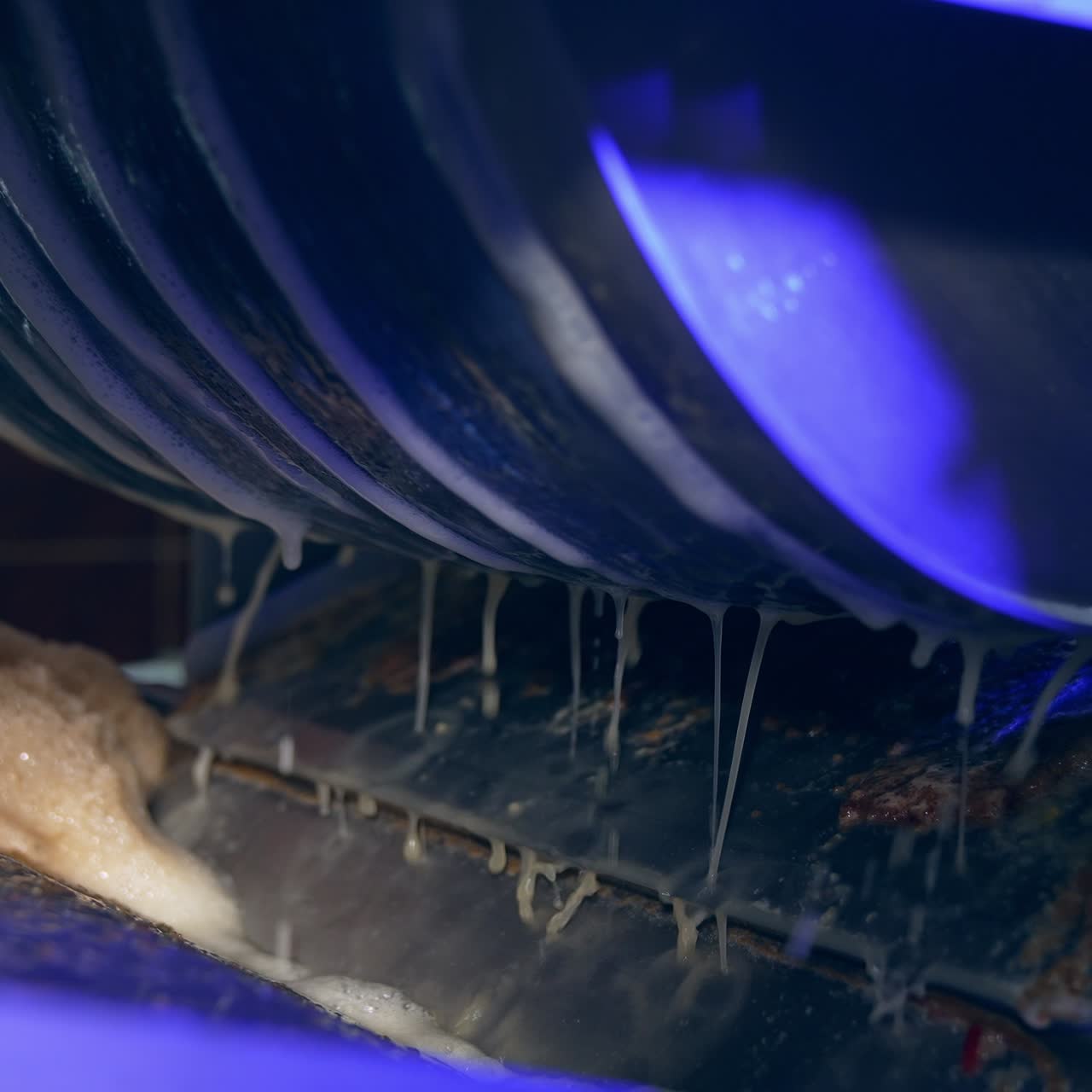Automated line for production healthy food products. Rotating mechanism at a food factory with fresh juice dripping from it. Close up
