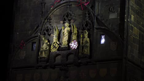 charles bridge in prague, czech republic in the night close up on the christian religious sculptures with golden details that are lighten up with the eagle and lion emblem representing czechia