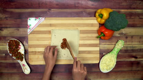 a top view of spreading mince for spring roll, two big yellow and red chili and a green broccoli on the table