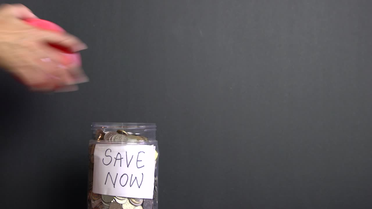 "그녀는 ""돈을 절약하라""라는 표지판이 붙은 용기 안에 동전을 넣고, ""비가 오는 날을 위해 돈을 절약하십시오."""