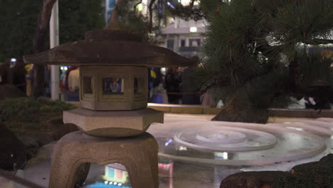 japanese traditional toro and pine tree in front of shibuya station