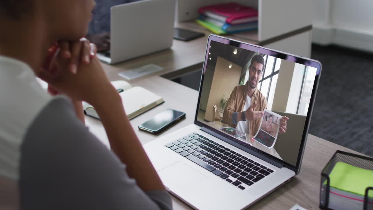 African american woman having a video conference on laptop with male office colleague at office