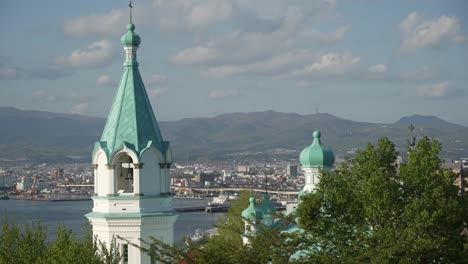 Close-Up-View-Of-The-Stunning-Roof-Of-Orthodox-Church-With-Hakodate-Bay-And-Mountains-In-Distance-At-Motomachi-District-In-Hokkaido,-Japan