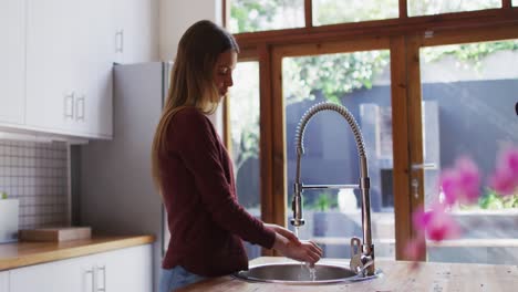 woman washing her hands in the sink at home