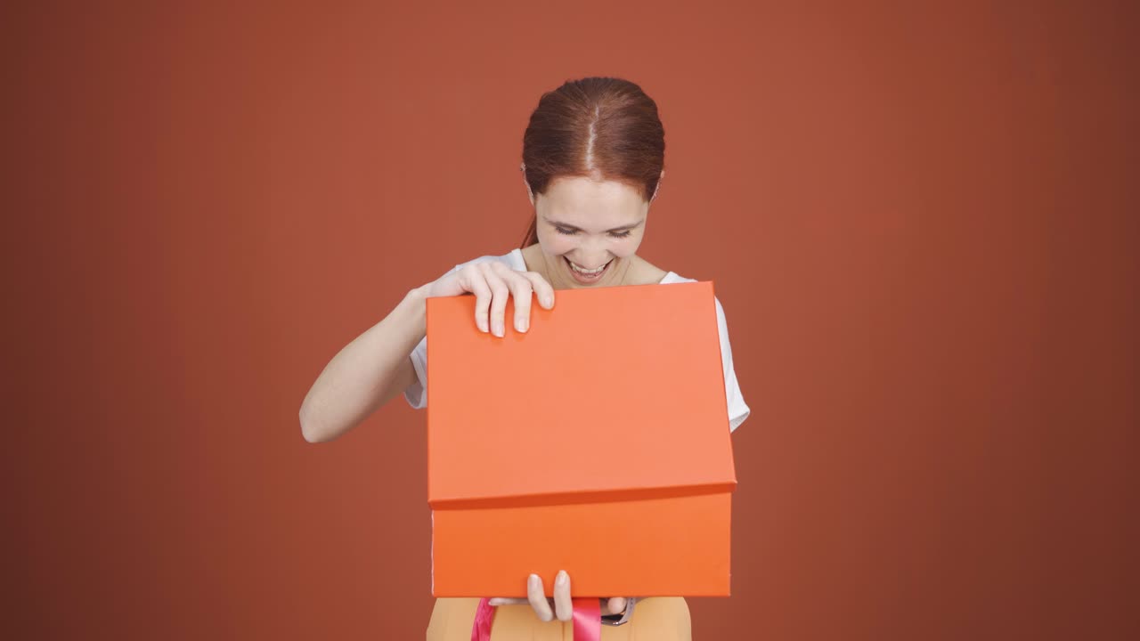 행복하고 즐거운 여자가 선물 패키지를 열고 있습니다.