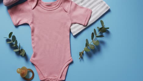 video of pink baby grow, booties and hat with copy space on blue background