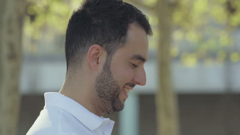 Side-view-of-handsome-young-man-walking-on-street-and-laughing.