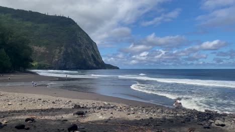 people enjoying calm waves at waipio valley beach on big island