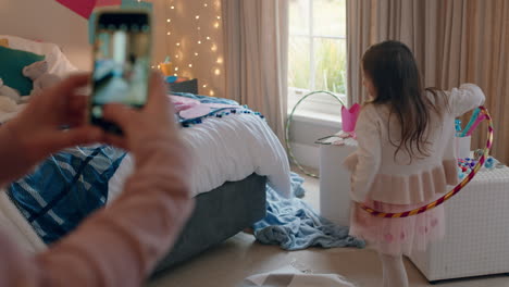 niña feliz jugando con hula hoop en un dormitorio colorido con su madre tomando fotos usando un teléfono inteligente compartiendo en las redes sociales