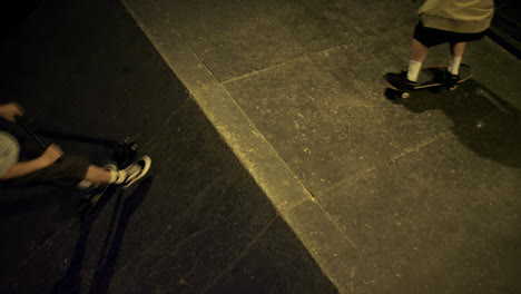 jinetes adolescentes entrenando juntos en el skatepark con pared de graffiti por la noche.