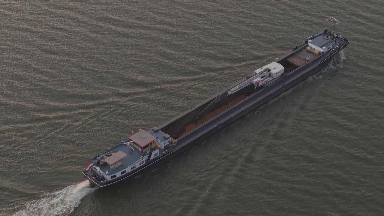 해가 지는 동안 ijsselmeer에서 모래를 항해하는 화물 선박의 위쪽 내려다보기, 항공