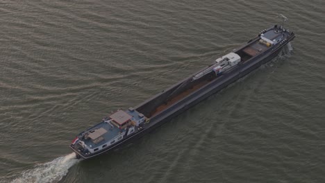 top down view of cargo ship with sand cruising on ijsselmeer during sunset, aerial