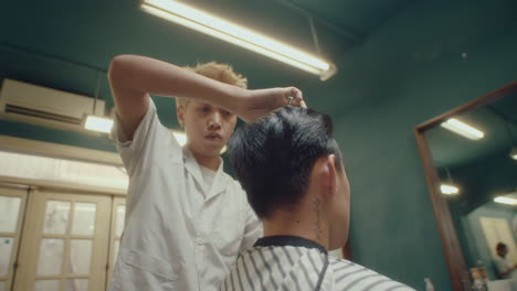 asian barber checking evenness of haircut of client