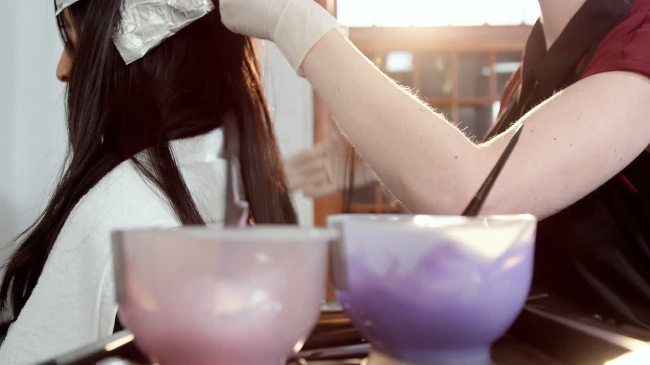 Parrucchiera che tinge i capelli della sua cliente