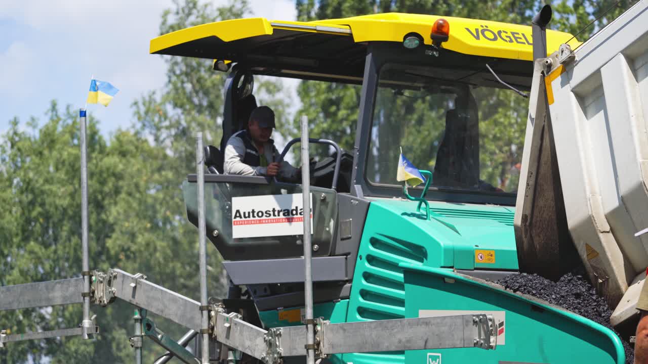 Road machinery for laying asphalt. Industrial pavement truck outdoors. Road repairs. Driver sitting in a truck during roadworks.