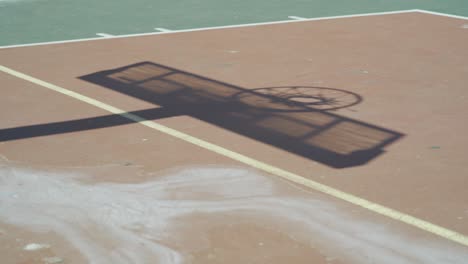 shadow of a basketball board on used outdoor court