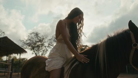 a woman gently pets a horse under a bright sky