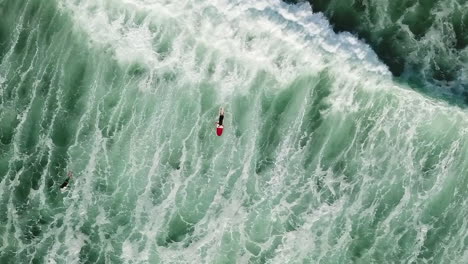 a surfer is dwarfed by the huge ocean waves that crash and sweep him under - straight down aerial view