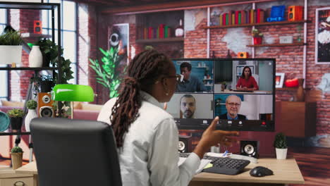 manager greeting employees during videocall from home, looking over paperwork