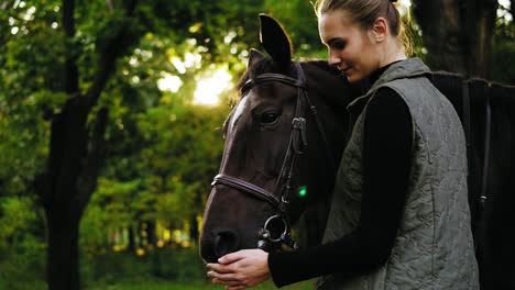 lens flare in the forest: young beautiful woman petting brown horse on a sunny day