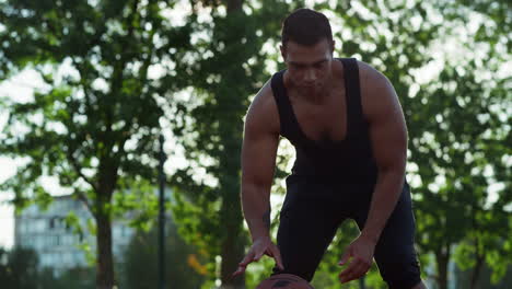 mixed race streetball player practicing basketball in sport playground.