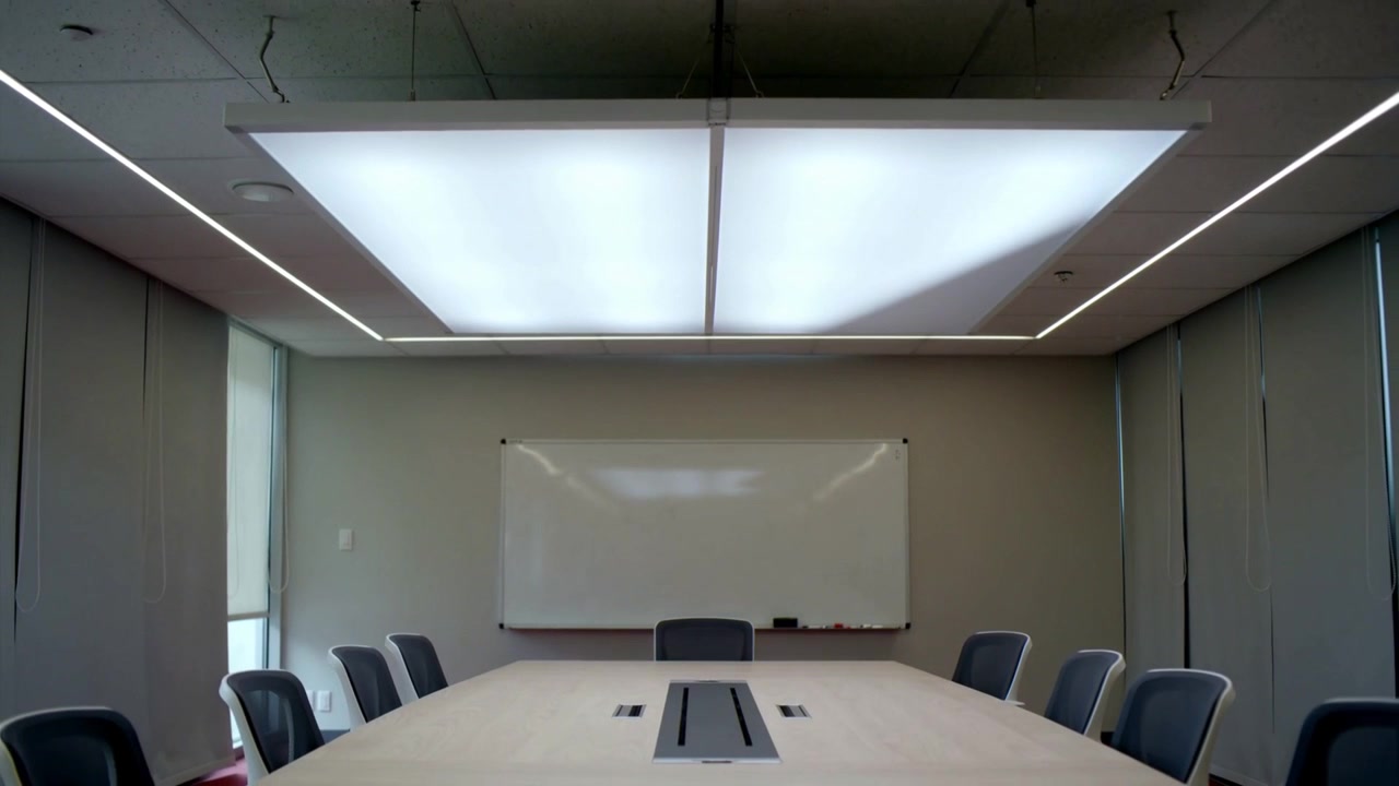 Shifting camera revealing meeting table and chairs in office meeting room to show ceiling light