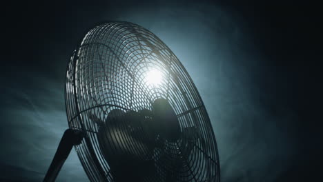 fan blades rotate in rays of light and fog. slider shot