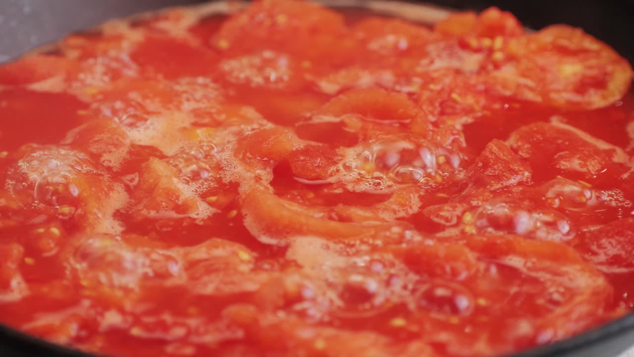 Cooking fresh peeled canned tomato Juice sauce in pan, peeled tomatoes boiling in their own juice, making tomatoes pasta sauce .Top view close up, Italian traditional cuisine food.