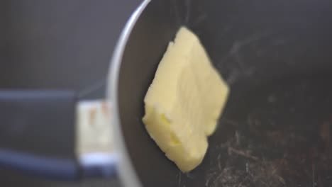 static shot of a man placing a stick of butter in to a pan