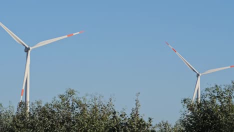 two windmill wind turbines in field, handheld shot