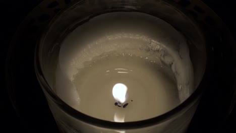 close up of candle holder with single flame and melted wax locked off