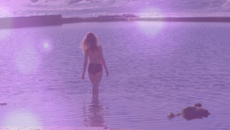 woman wading into coastal water under warm glow, overlaying heart rate chart for health
