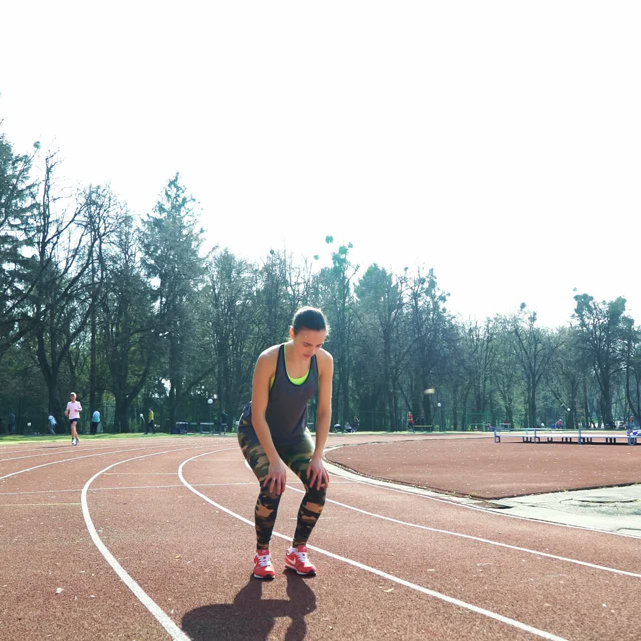 young fitness woman runner stretching legs on stadium track