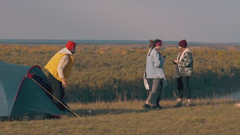 tourist gets out of blue tent and stretches near girls